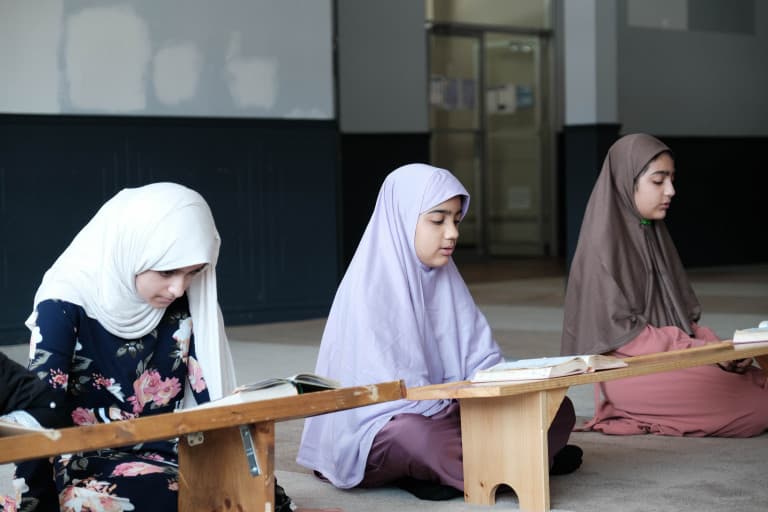 Girls reciting the Quran at wooden desks